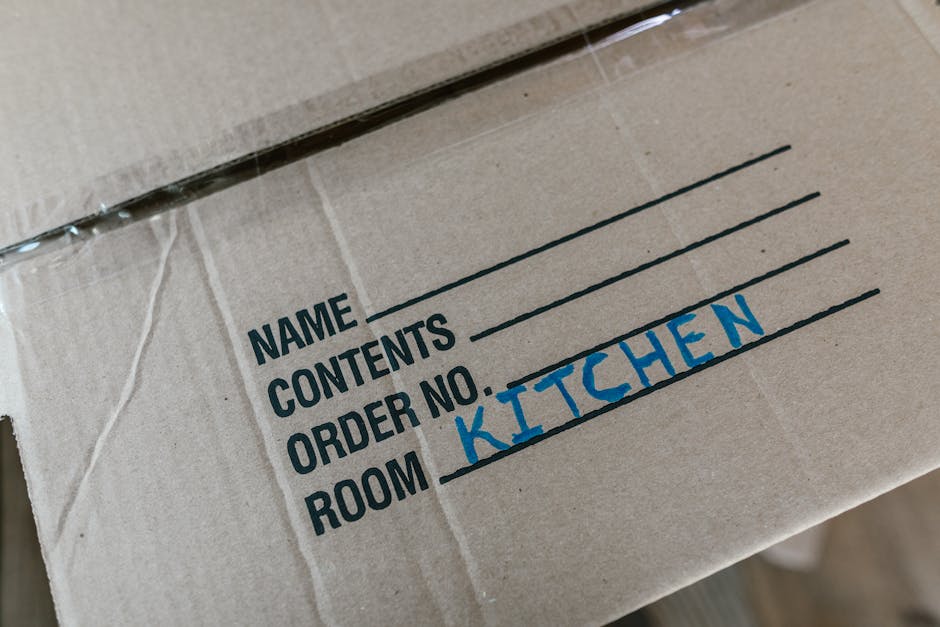 A pile of black garbage bags, cardboard boxes, and packaging materials stacked against a weathered red door set into a rough-textured, light-colored wall. Some of the bags appear to contain household